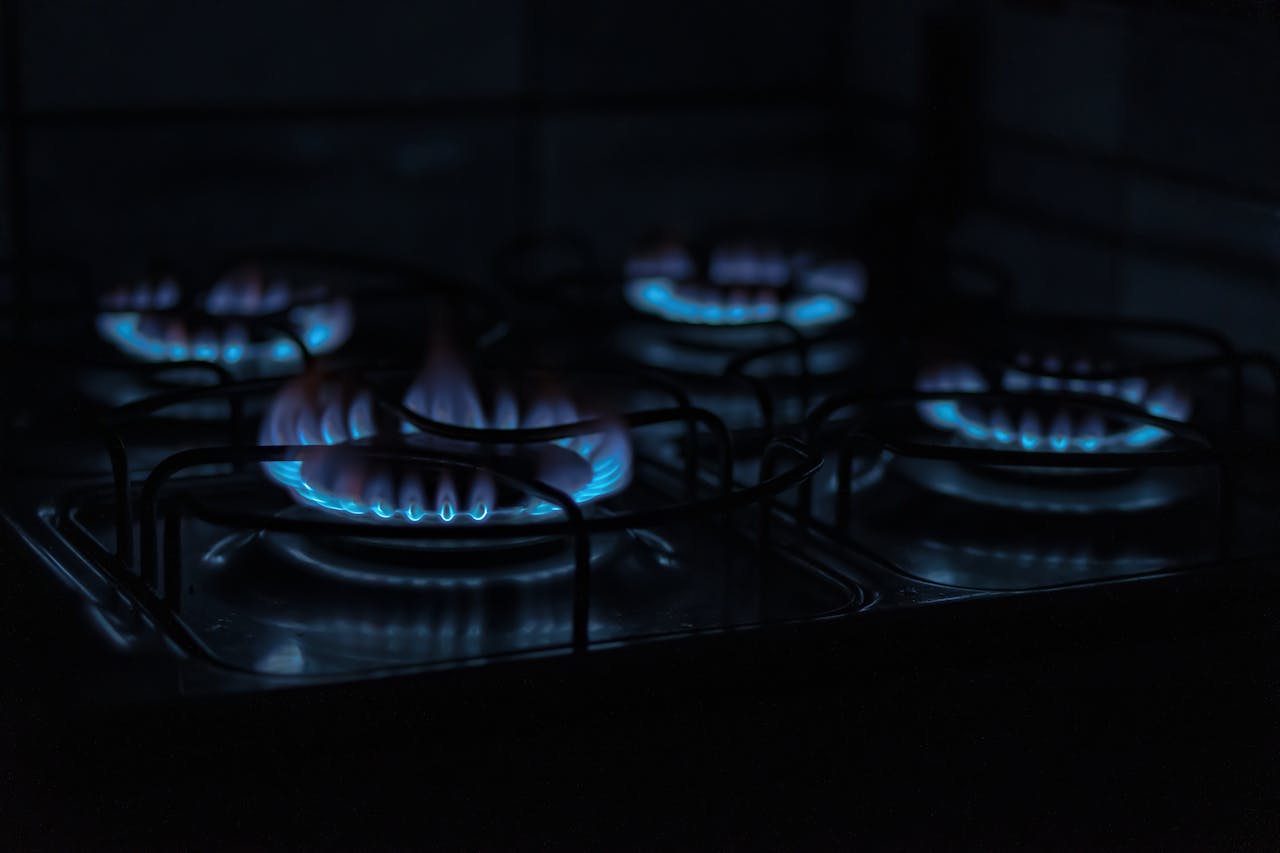 The Art of Drawing Readers In: Your attractive post title goes here A dark, atmospheric image capturing the blue flames of gas stove burners indoors.